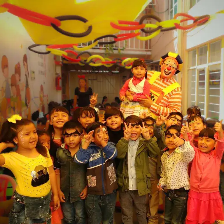 El Payaso Payín posa con un grupo grande de niños sonrientes al terminar un show infantil