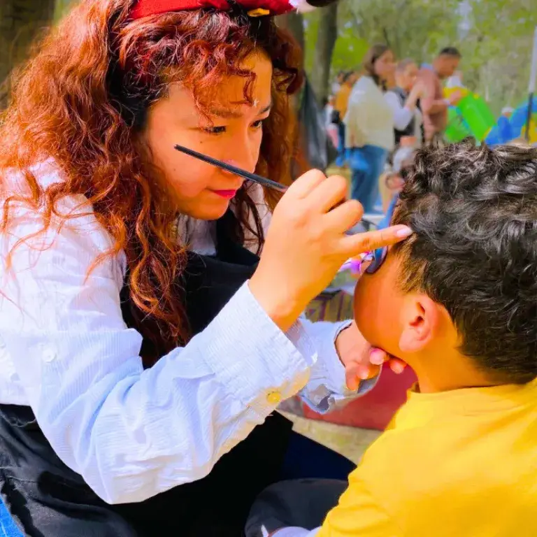 Una maquillista de Payasos Payín pinta la carita de un niño durante una fiesta infantil