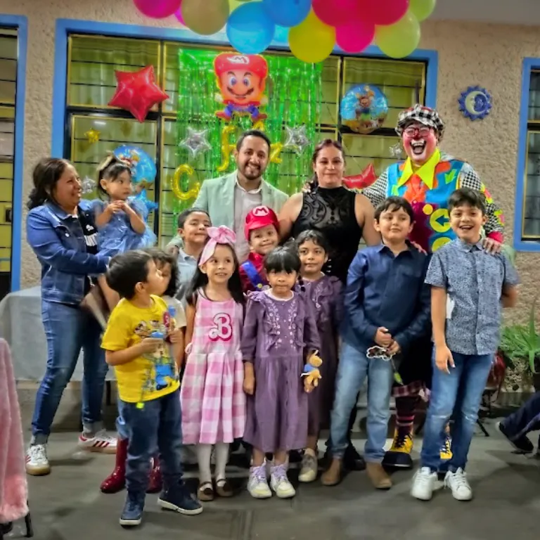 Familias e invitados posan con el Payaso Payín al terminar un show infantil