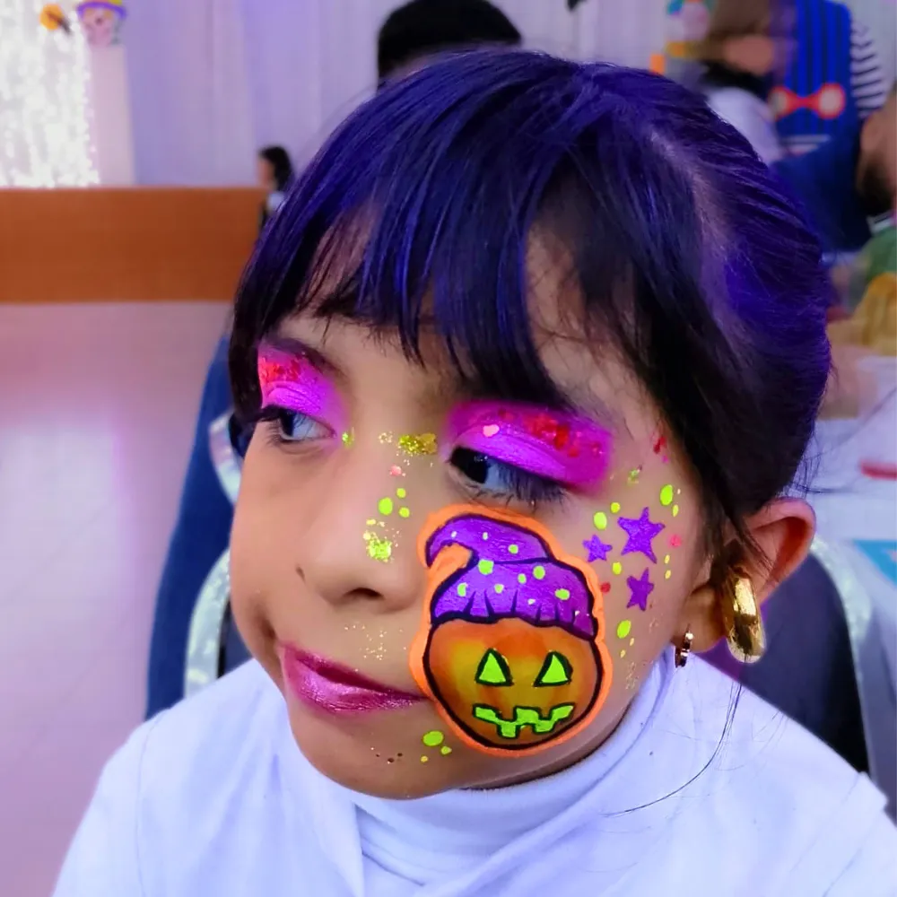 Pintacaritas de calabaza con sombrero de brujita morado y sombras fucsia neón para niñas en Halloween CDMX y EDOMEX