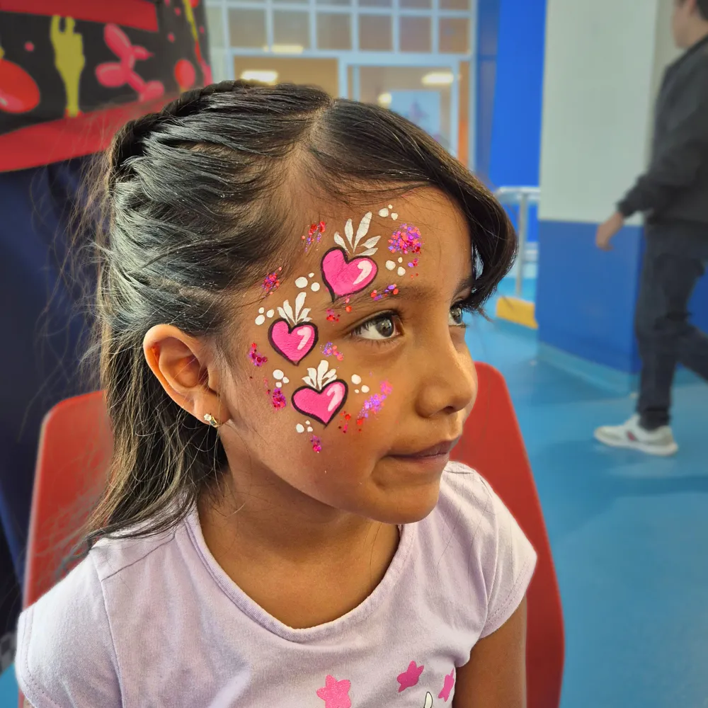 Pintacaritas de corazones en degradado rosa con glitter y filigranas blancas para niñas en fiestas infantiles CDMX