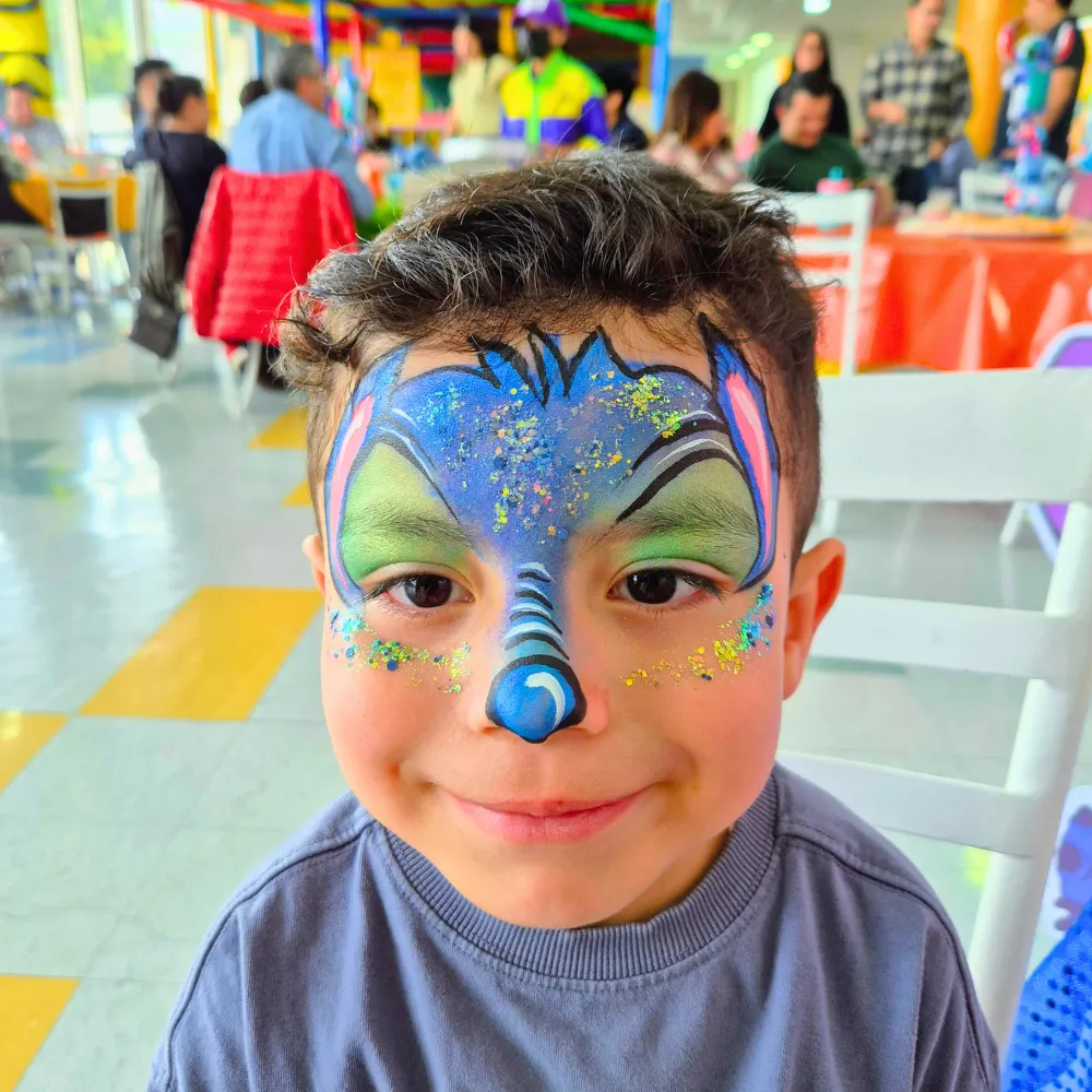 Niño con pintacaritas de Stitch con orejas grandes y glitter en fiesta infantil CDMX