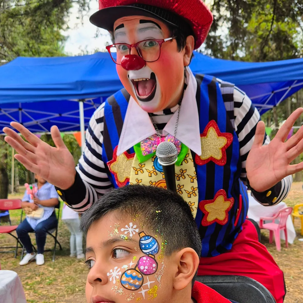Niño con pintacaritas de esferas navideñas y copos de nieve junto al Payaso Payín en fiesta infantil CDMX y EDOMEX