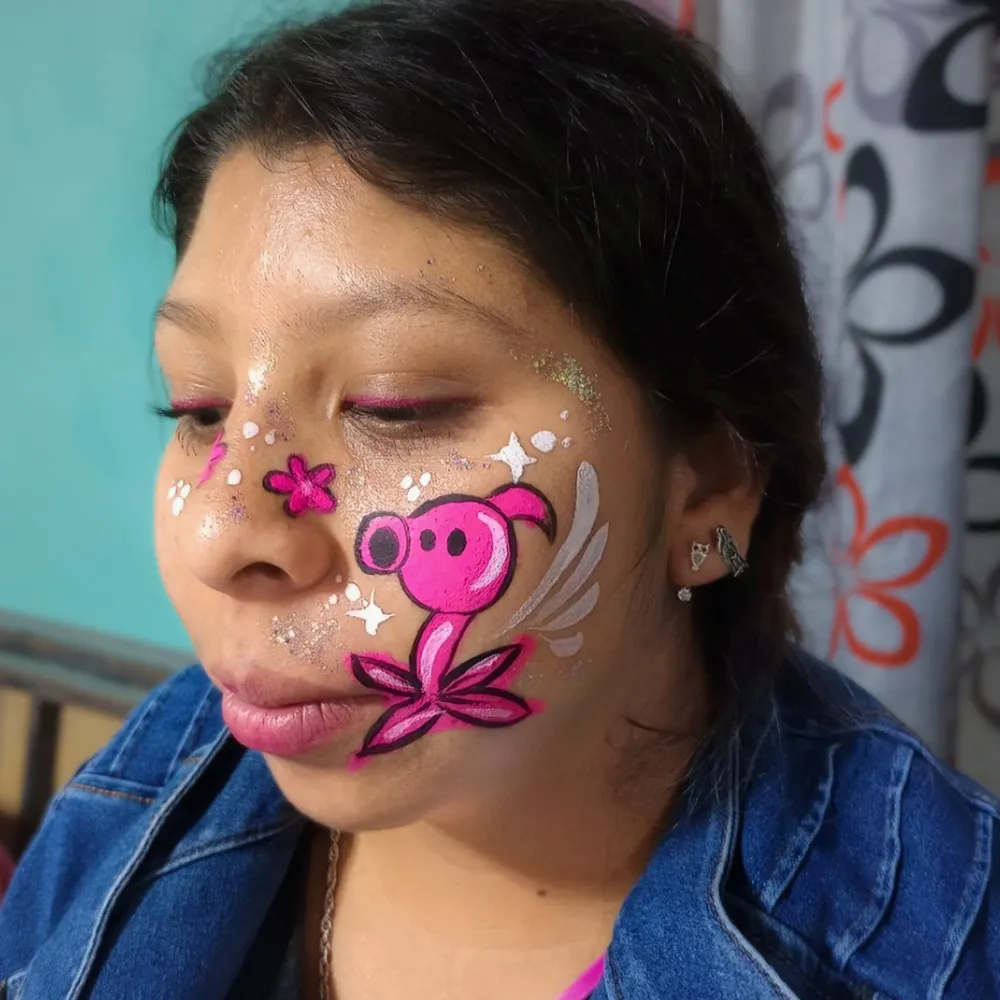 Pintacaritas de lanzaguisantes rosa de Plants vs Zombies en mejilla con flores y destellos para jóvenes en CDMX y EDOMEX