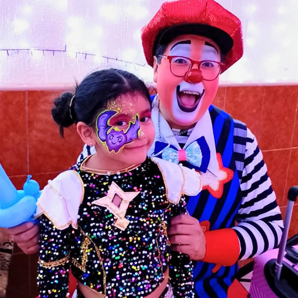 Niña con pintacaritas de murciélago morado kawaii con luna y glitter junto al Payaso Payín en CDMX y EDOMEX