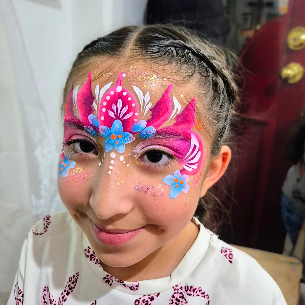 Pintacaritas de tiara floral en tonos fucsia y azul con filigranas blancas y glitter para niñas en CDMX y EDOMEX